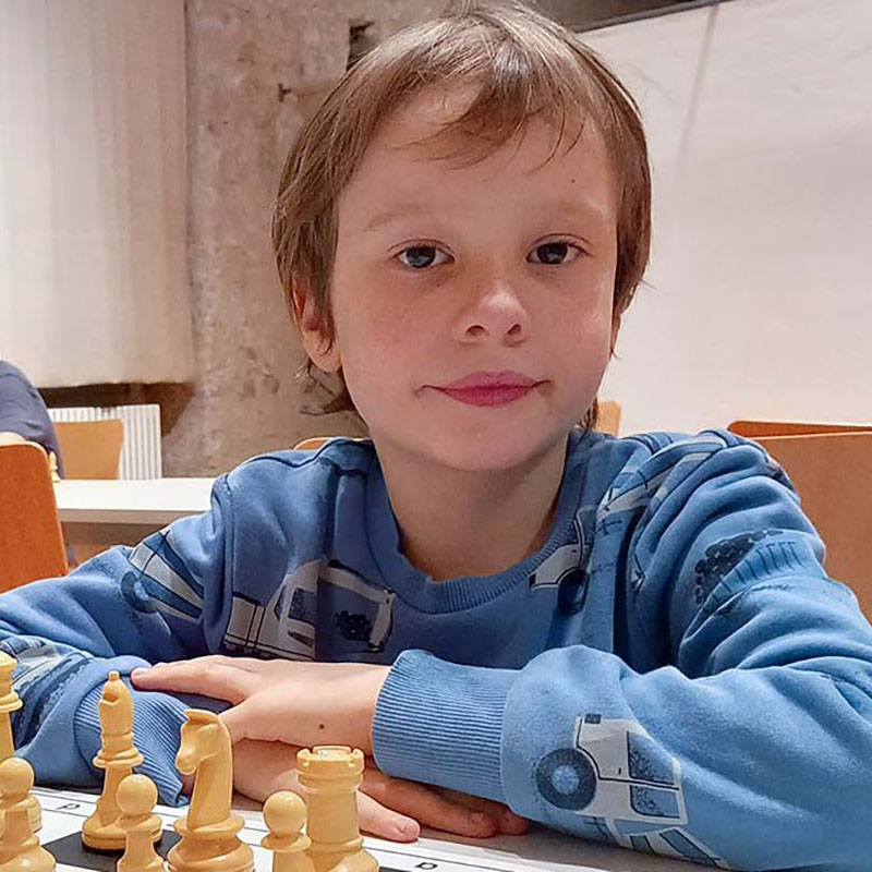 Der Junge lächelt, während er Schach spielt