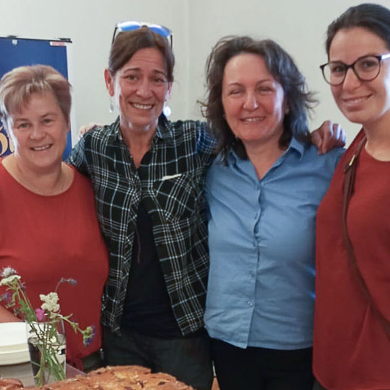 Vier Frauen posieren für ein Foto neben einem Tisch mit Essen